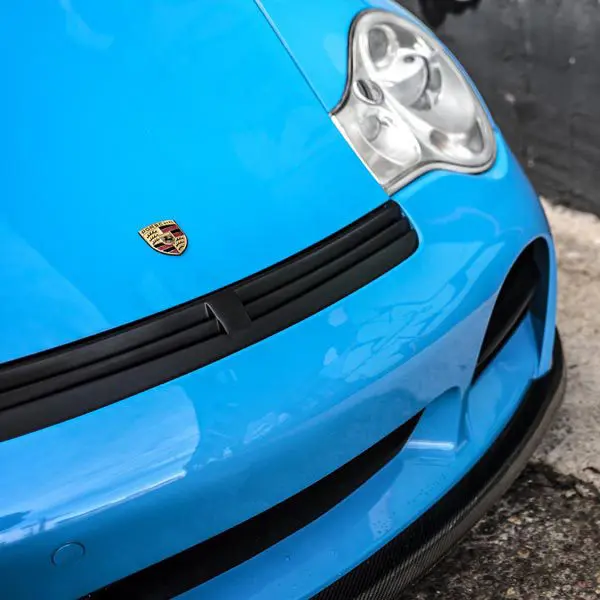 Blue Porsche front with logo and headlight.