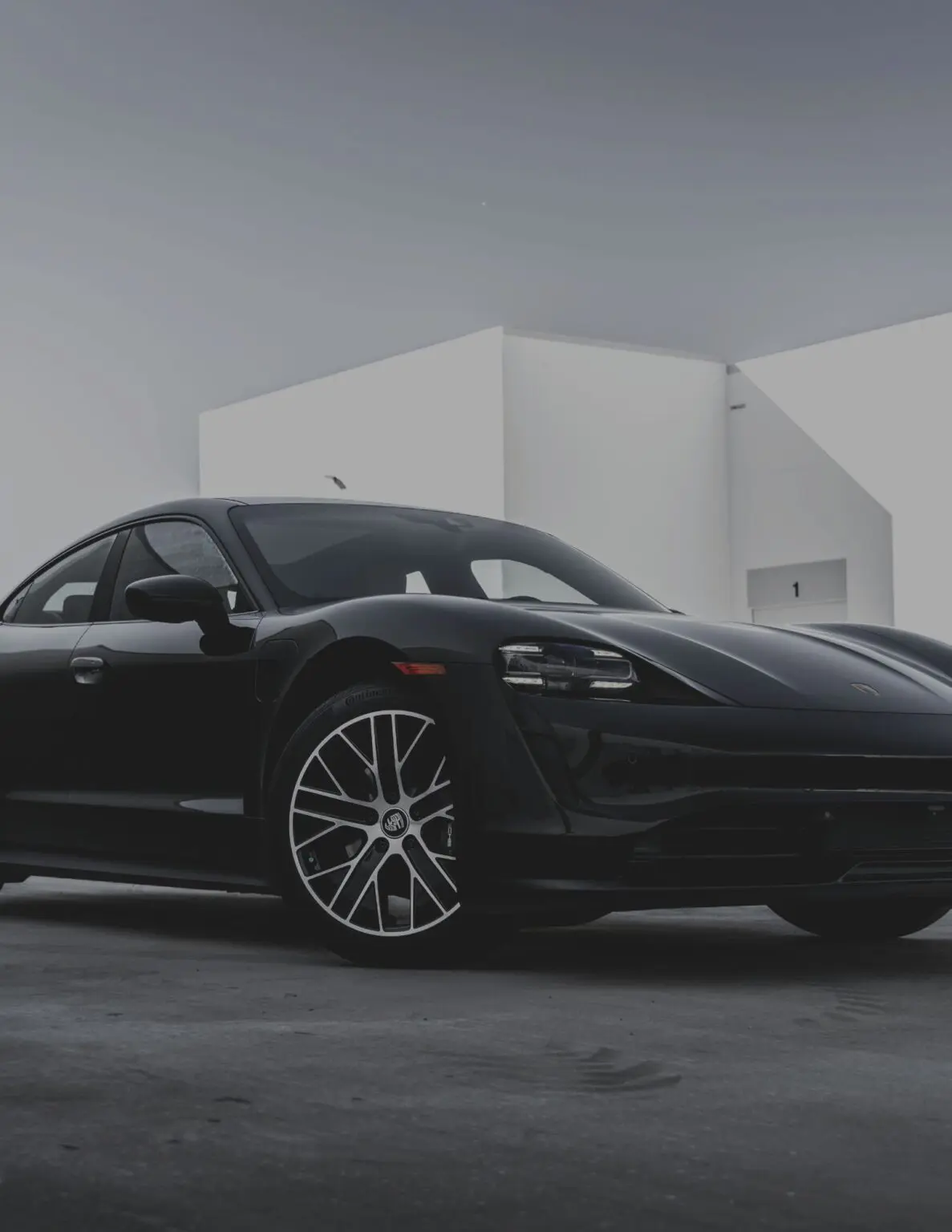 Black sports car parked near white building.
