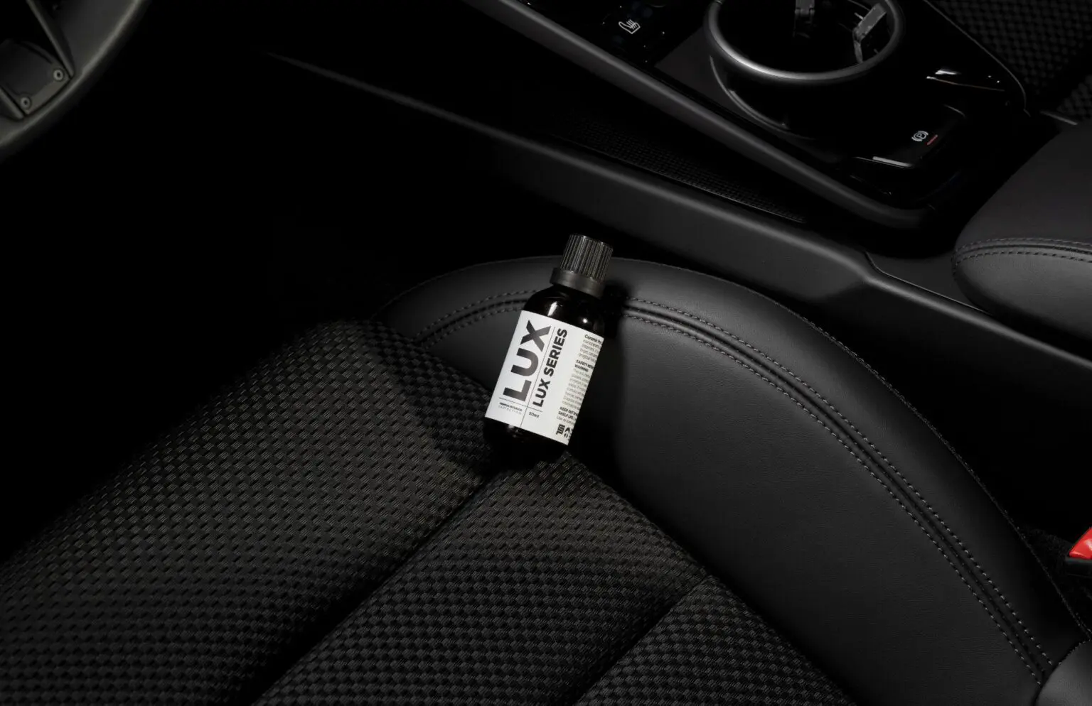 Bottle on car seat with black interior.