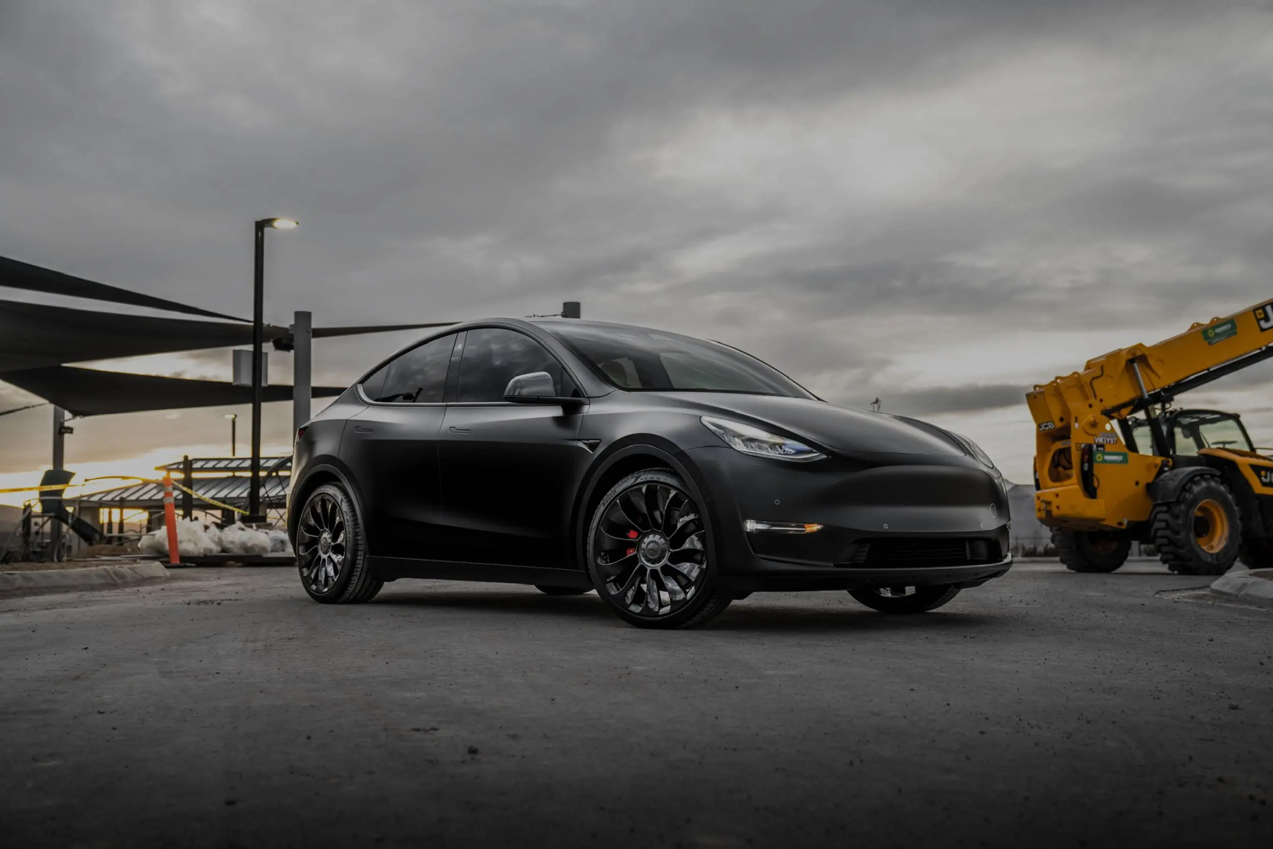 Black electric car parked under cloudy sky.