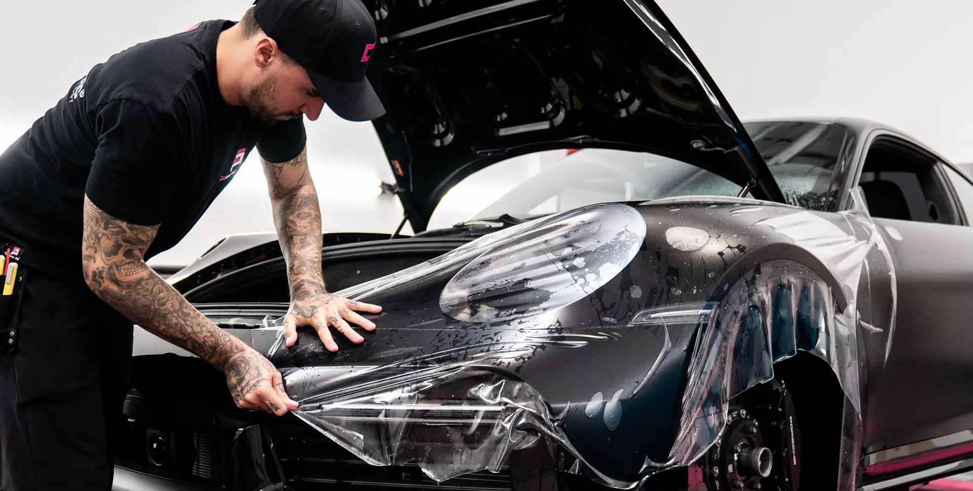 Man applying protective film on car.