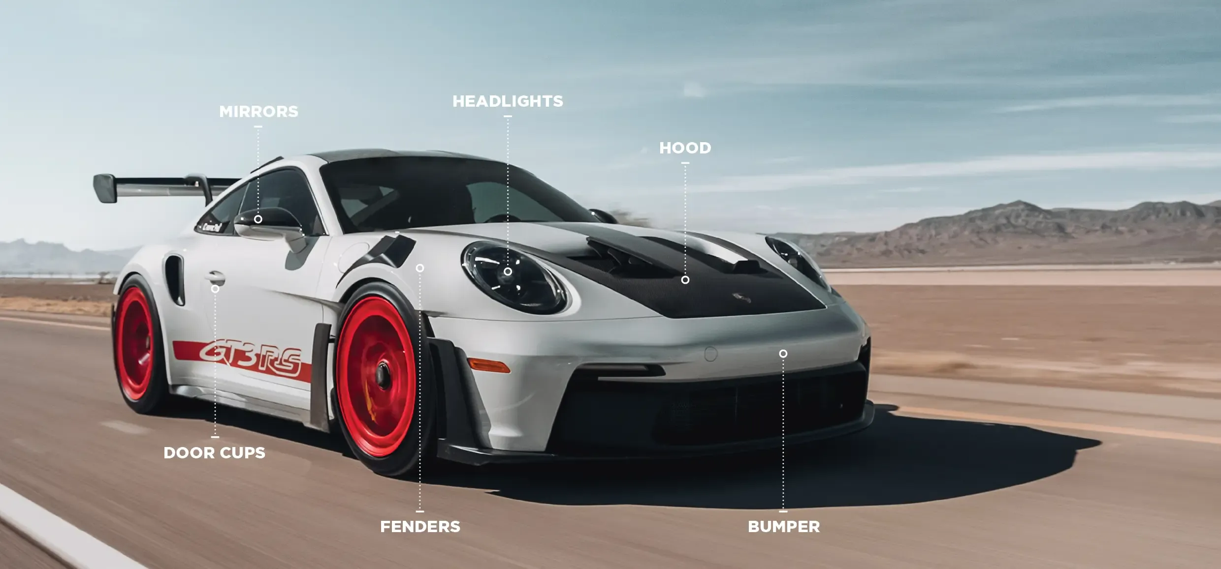 White sports car with red wheels driving fast.