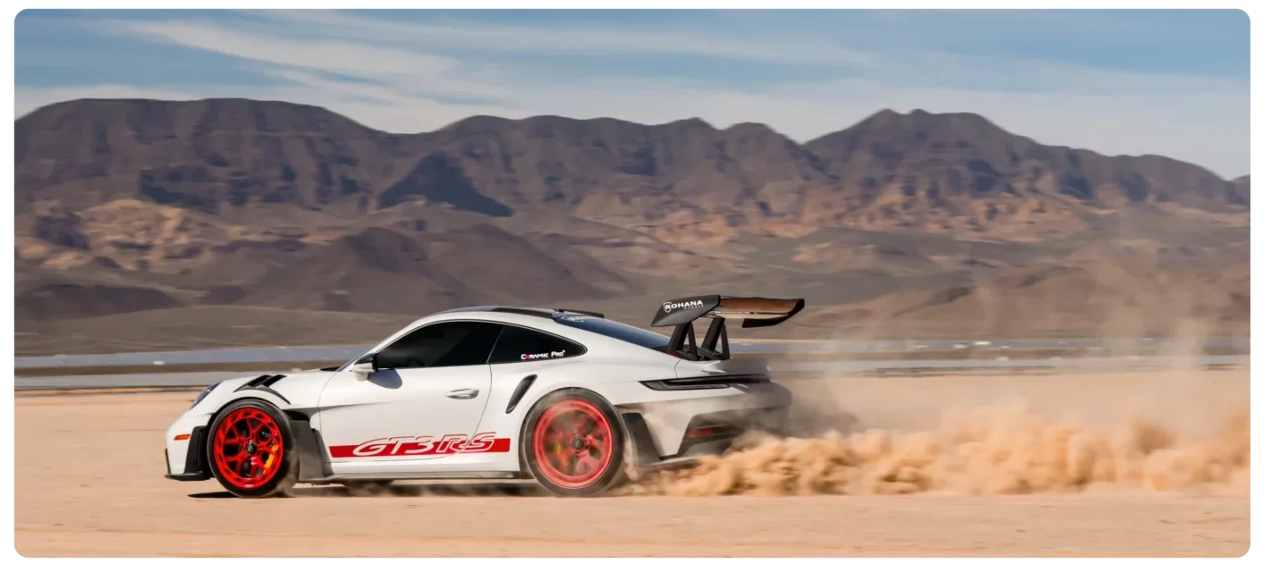 Sports car speeding on desert landscape.